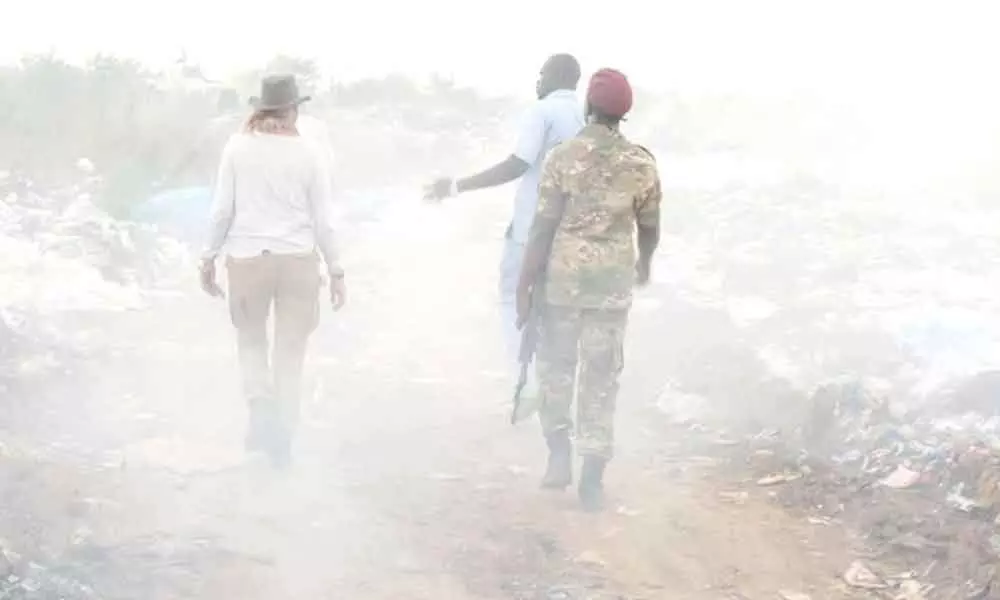 Crawford walks through land filled with plastic waste