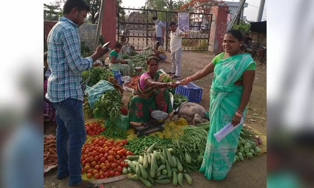 A village volunteer handing over pension money  to a beneficiary at Gajapathinagaram market in Vizianagaram district on Monday