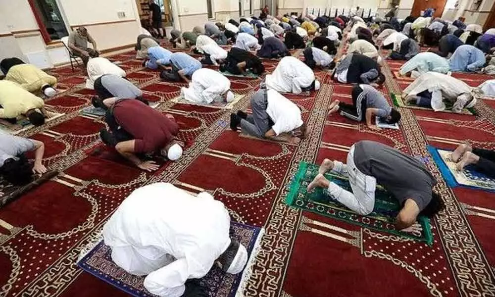 Social distancing and wearing masks, with some wearing gloves to guard against the new coronavirus, Muslim men pray at the Islamic Center