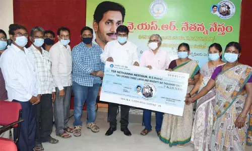 Collector R Muthyala Raju handing over cheque for Rs 2.03 crore to beneficiaries in Eluru