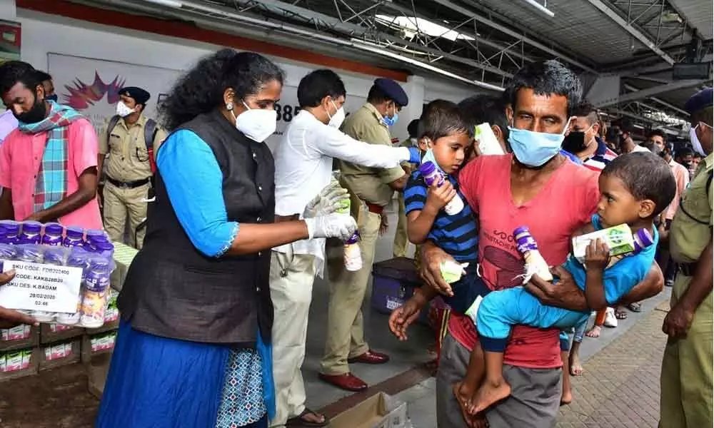 Amruta Hastam founder Karuna Sri distributing fruit juice to migrant workers at Vijayawada Railway Station on Monday