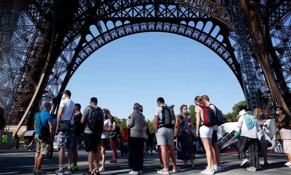 People queue up prior to visit the Eiffel Tower, in Paris on Thursday. The Eiffel Tower reopens after the coronavirus pandemic led to the iconic Paris landmarks longest closure since  World War II