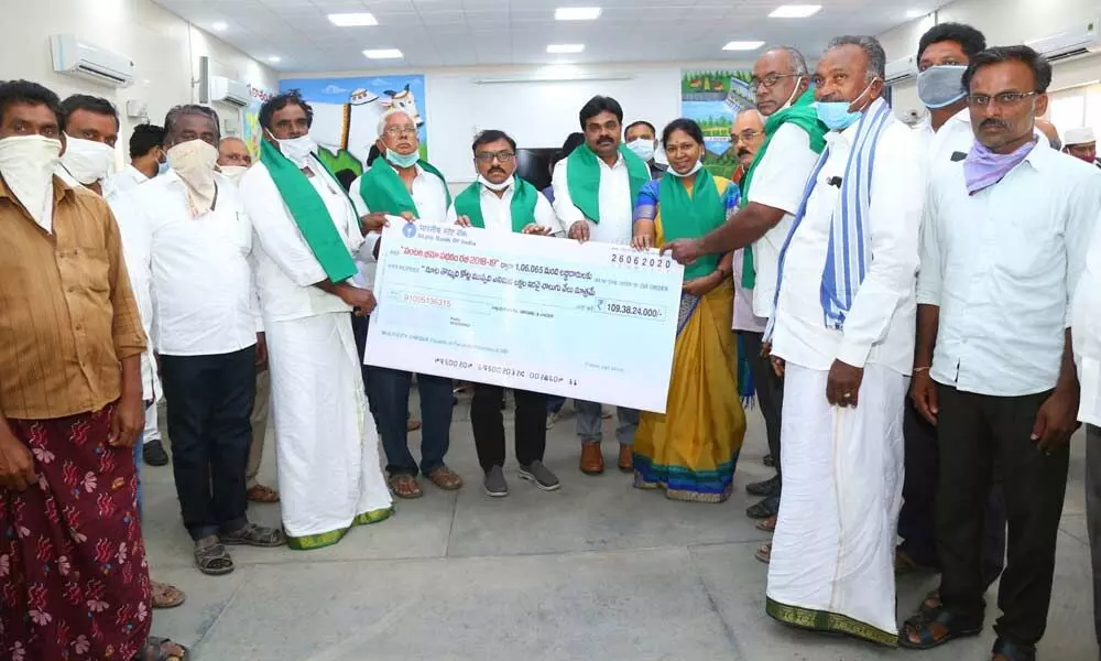 Prakasam District Collector Dr Pola Bhaskara distributing insurance benefit to the farmers in the district in Ongole on Friday