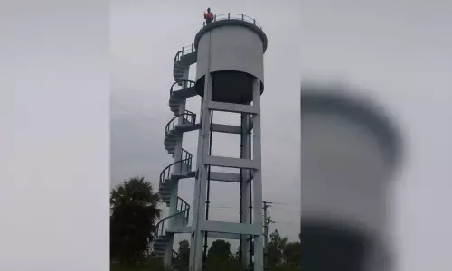 A farmer, Satish, atop water tank with petrol bottle in Ippalapally village on Wednesday