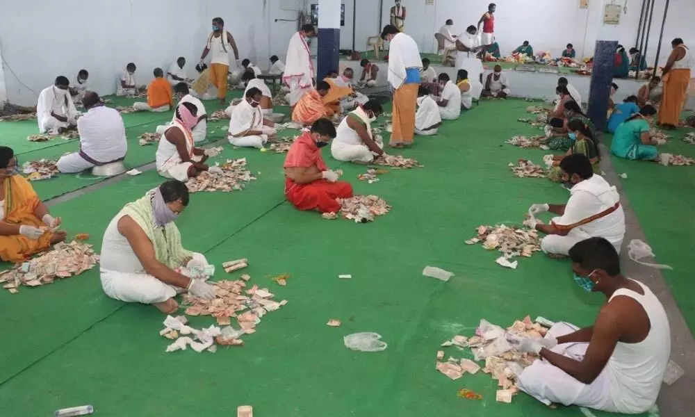 Temple staff counting hundi collections on Sri Raja Rajeswara Swamy temple premises in Vemulawada on Thursday