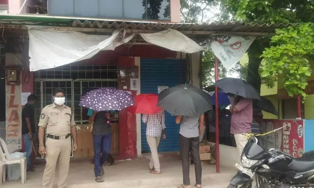 Boozers waiting in queues with umbrellas to purchase the liquor in Kakinada on Friday