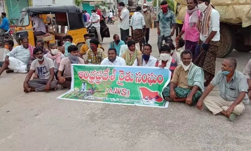 Farmers staging a road blockade in front of Tekke Agriculture Market Yard in Nandyal on Friday