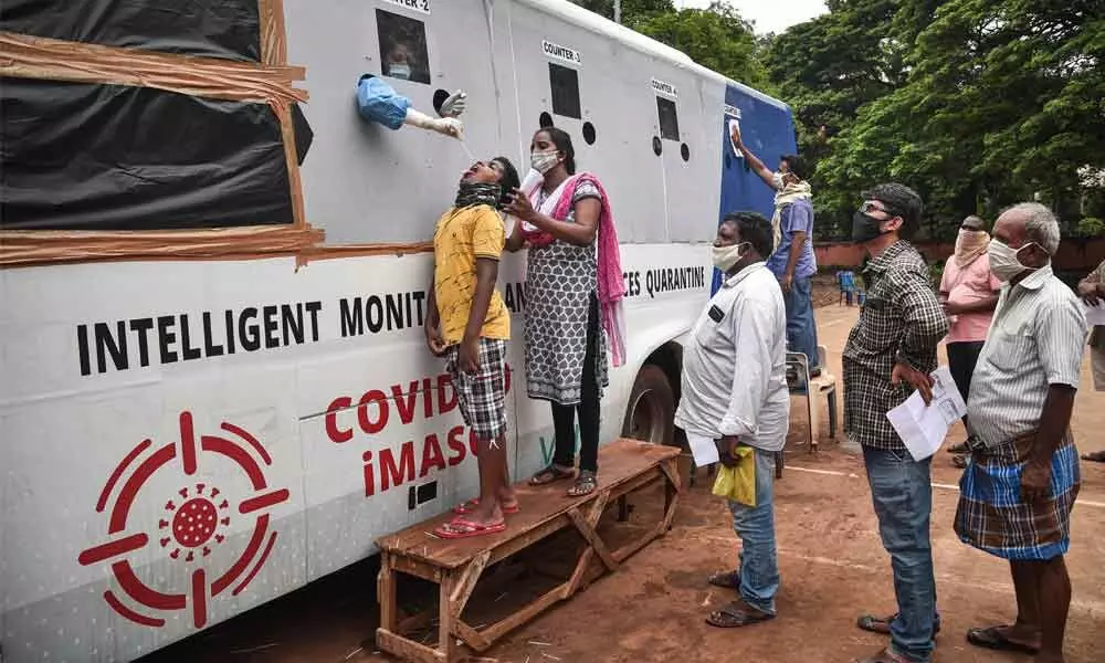 A medic collects samples for Covid-19 test from a mobile swab collection vehicle at Indira Gandhi Municipal Corporation Stadium in Vijayawada on  Friday