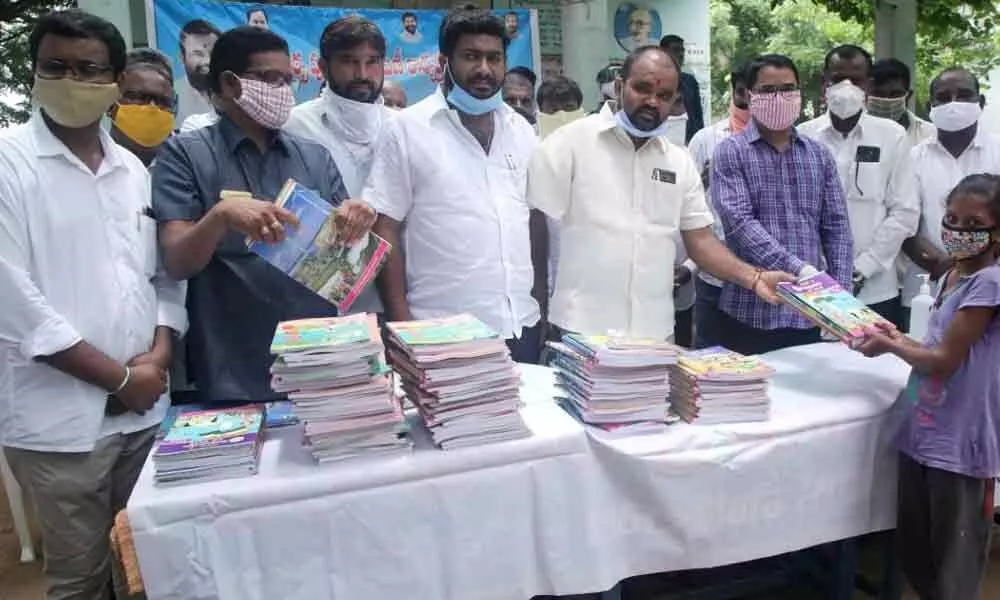 MLA Kancharla Bhopal Reddy distributing books and masks to the school students at Government Primary School of Katalguda