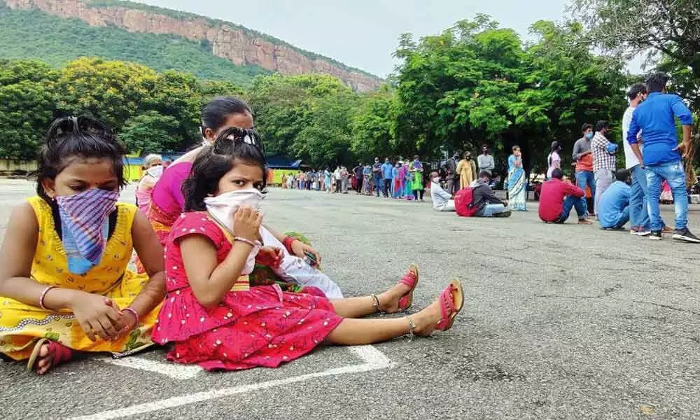 People, including children wait in queue to give swab for  test at Sanjeevini bus at Alipiri link bus stand in Tirupati on Tuesday