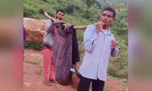 A pregnant woman being carried on a doli to access an ambulance at Panasabanda in Visakhapatnam district