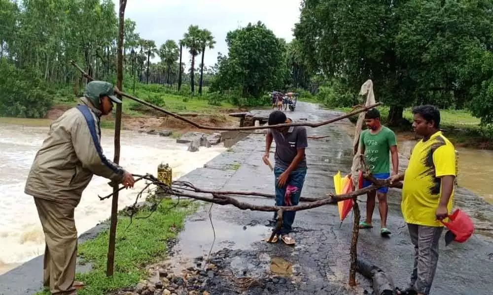 Officials blocking traffic on a bridge damaged by Godavari flood at Kunavaram in East Godavari district on Saturday