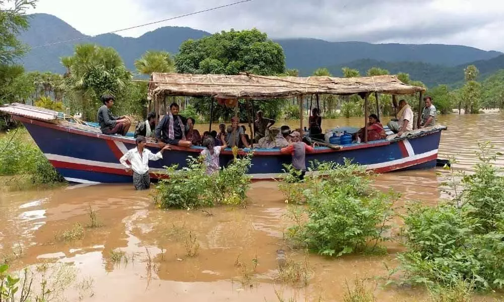 Villagers travelling on boats in floodwater in Kunavaram mandal in East Godavari on Wednesday