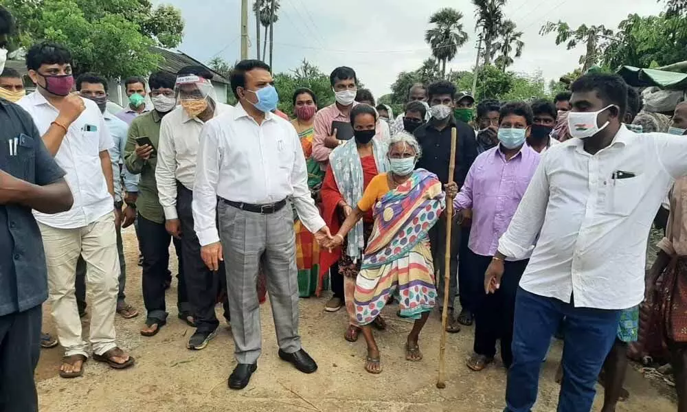 District Collector Dr MV Reddy helping an old woman to walk during his visit to Kashis Nagaram village on Wednesday