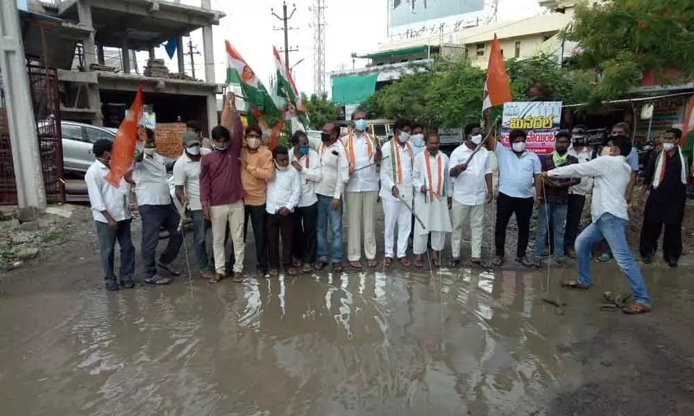 Congress leaders catching fish in stagnated water in front of Ambedkar stadium in Karimnagar city on Friday