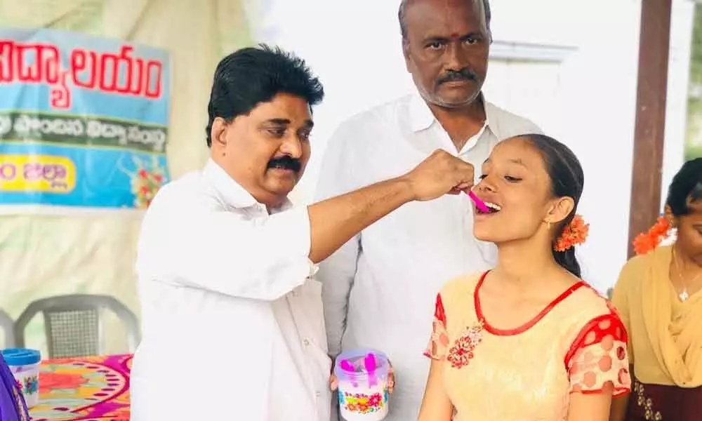 Senior TRS leader Dr M Dayanand administering homeo medicine to a girl in Sathupalli on Tuesday