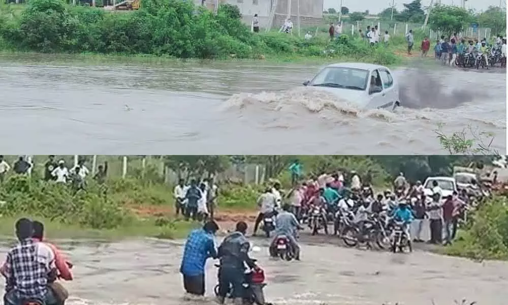 A car wading through heavy floodwater from Chepalavaagu on the road in Pebbair on Wednesday (Top); People on two-wheelers crossing the flooded road near Chepalavaagu in Pebbair on Wednesday (Bottom)