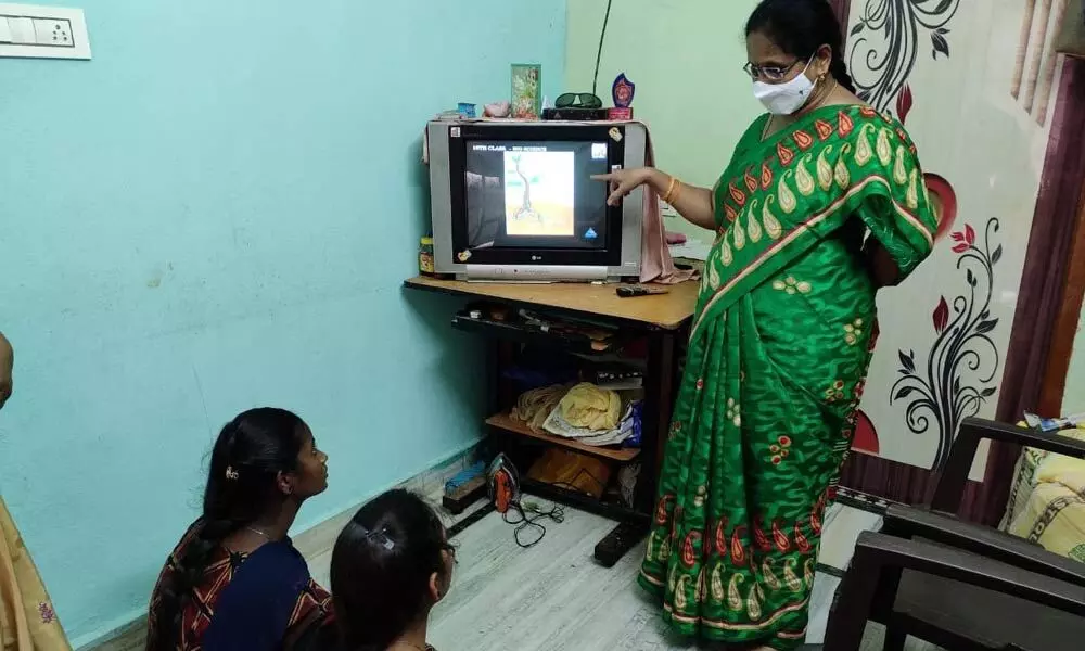 A teacher clarifying doubts of students during home visit in Warangal