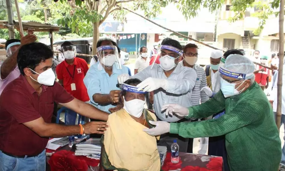 District Collector J Nivas fixing a face shield to a woman in Srikakulam as part of measures to prevent the spread of Covid-19