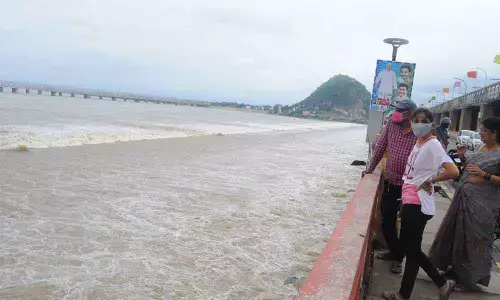 Visitors watching flood released into sea at Prakasam Barrage in Vijayawada on Sunday