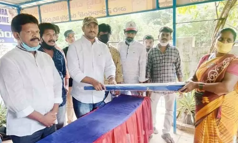 Swarnandhra Seva Samsta founder Dr Gubbala Rambabu distributing umbrellas to petty fish traders in Rajamahendravaram on Sunday