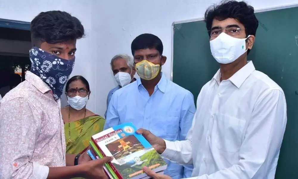 East Godavari District Collector D Muralidhar Reddy distributing notebooks to students at PR Government Boys High School in Kakinada on Monday