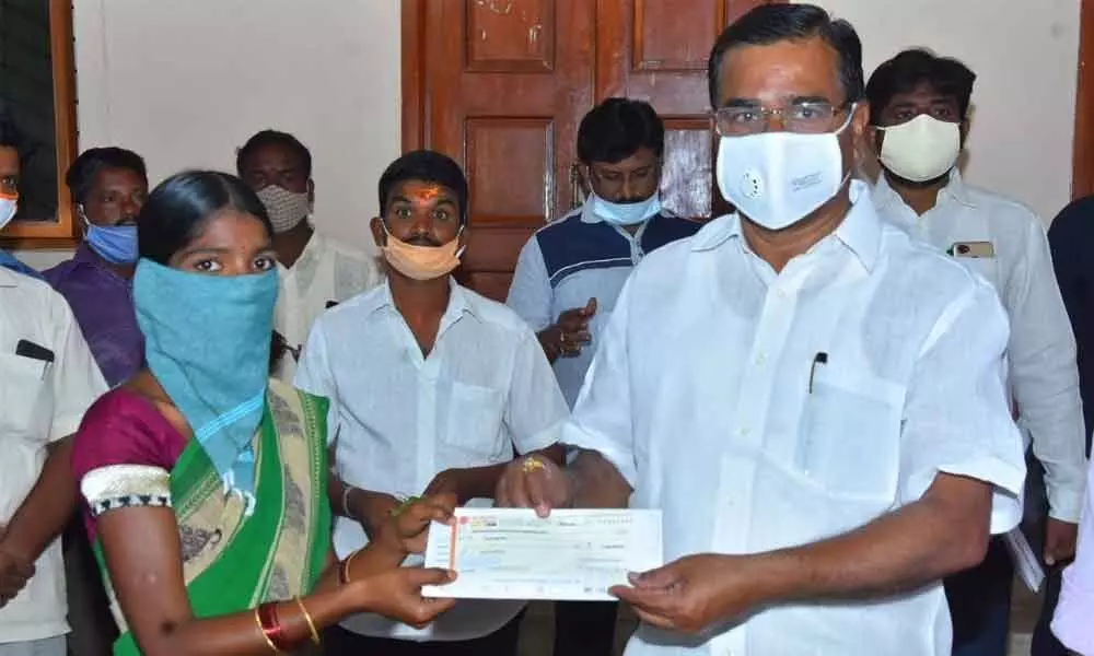 Agriculture Minister Singireddy Niranjan Reddy handing over a cheque for Rs 2 lakh to the wife of a TRS activists, who was killed in recent accident, in Wanaparthy on Thursday