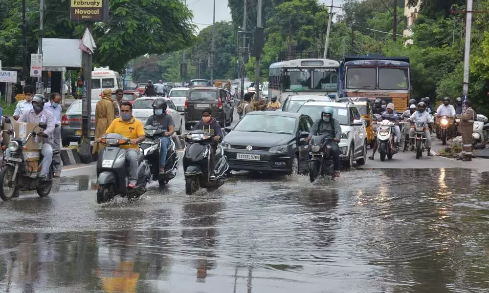 Traffic police not only channelizing traffic but also rain water at Karkhana in Hyderabad on Saturday