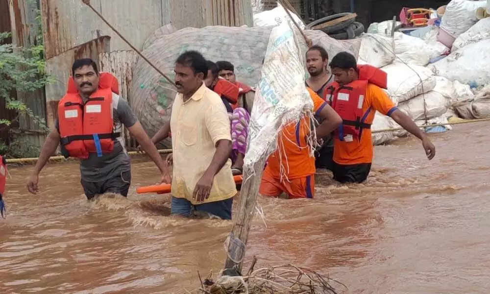 Rescue team members shifting people stranded in floodwater in a colony in Nandyal to a safer place on Sunday