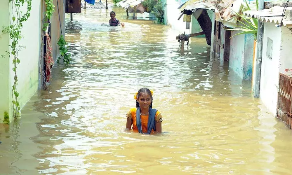 A girl wading through floodwater in Bhupesh Gupta Nagar