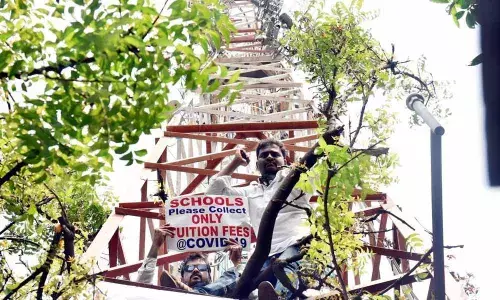 A parent staging protest on a cell tower in Visakhapatnam on Monday opposing hike in school fee