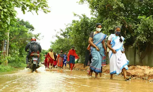Motorists and pedestrians wading through a waterlogged road in Tirupati on Sunday