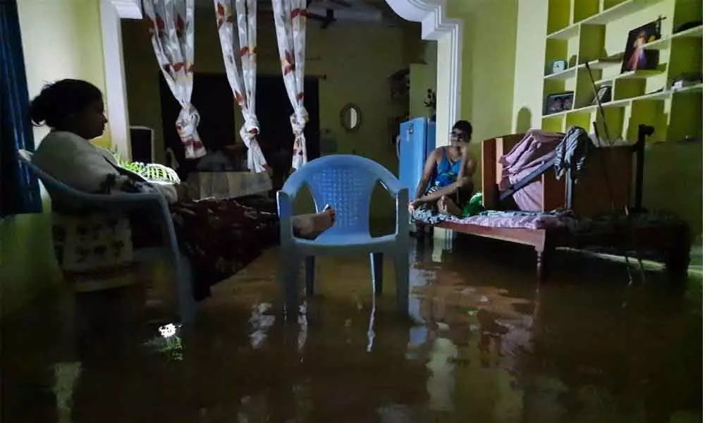 A family keeps themselves dry in a flooded home with no electricity in Damaiguda in Hyderabad on Tuesday. Photo: Ch Prabu Das