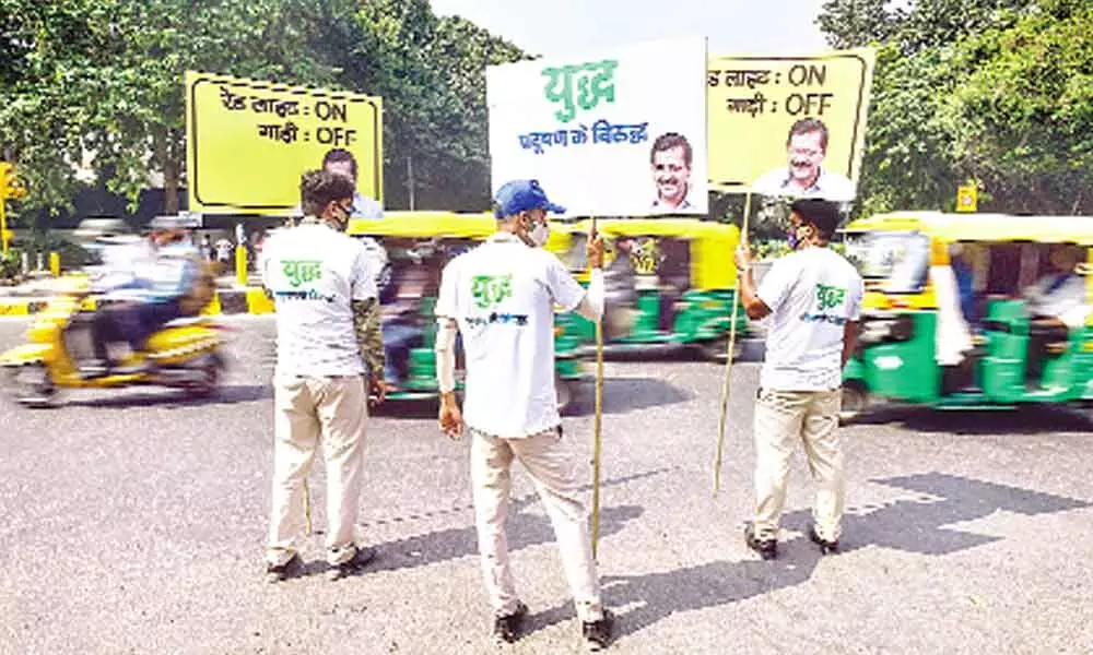 Civil Defence volunteers hold placards and request commuters to participate in the campaign Red Light On, Gaadi Off, launched by Delhi Government to tackle air pollution, in New Delhi on Thursday