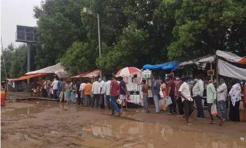 People waiting in long queues to get onions at Anand Bharathi Rythu Bazaar in Kakinada on Thursday