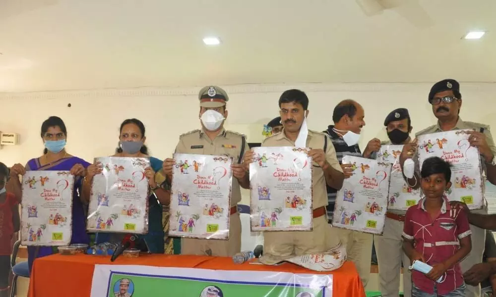 Police officials and others unveiling poster on childhood at a meeting with rescued children and their parents