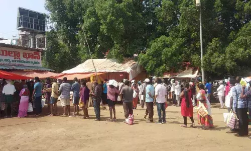 Consumers waiting in long queues to get subsidised onions at Anand Bharathi grounds Rythu Bazaar in Kakinada on Sunday