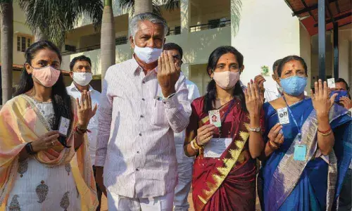 Congress candidate Kusuma H and her family members showing their inked fingers after casting votes for Rajarajeshwari Nagar Assembly by-polls in Bengaluru on Tuesday