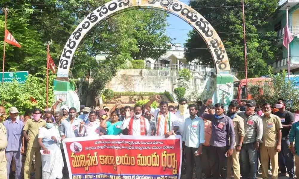 Municipal workers and union leaders staging a dharna before the Municipal Corporation office in Khammam on Tuesday
