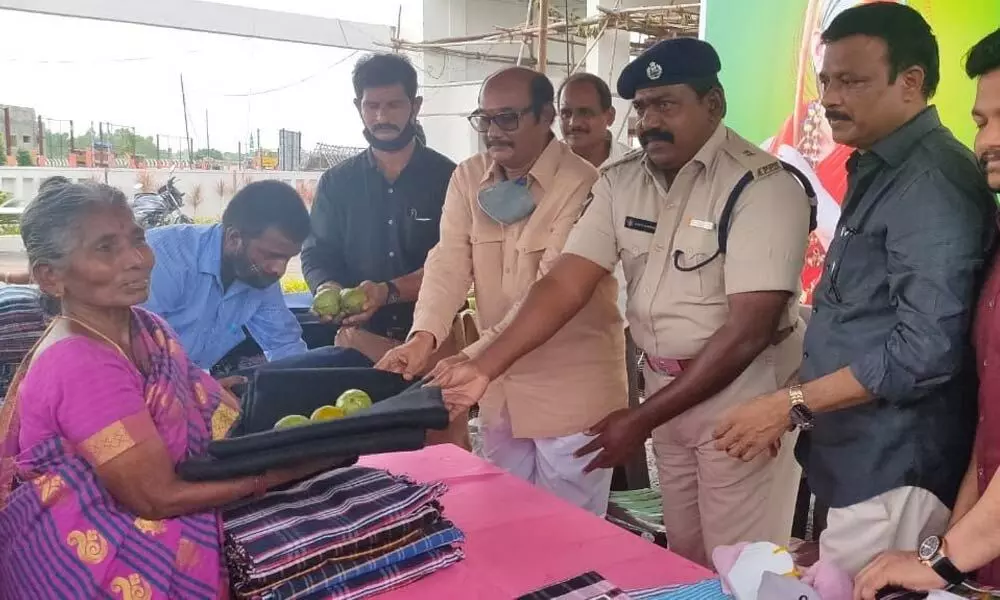 Additional SP B Ravichandra, Ravisankar and other guests distributing clothes to poor at Sai Vishnu Vilas in Chadalavada on Wednesday