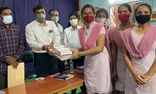 District Collector J Nivas distributing books to students to enable them to prepare of competitive examinations in Srikakulam on Thursday