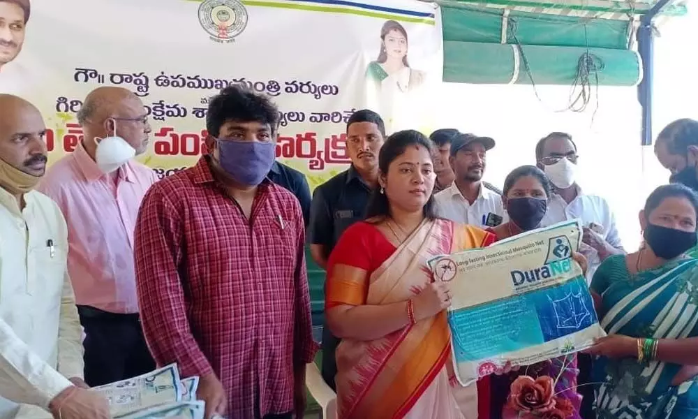 Deputy Chief Minister P Pushpasreevani distributing mosquito nets to people in Chinamerangi in Vizianagaram district on Friday