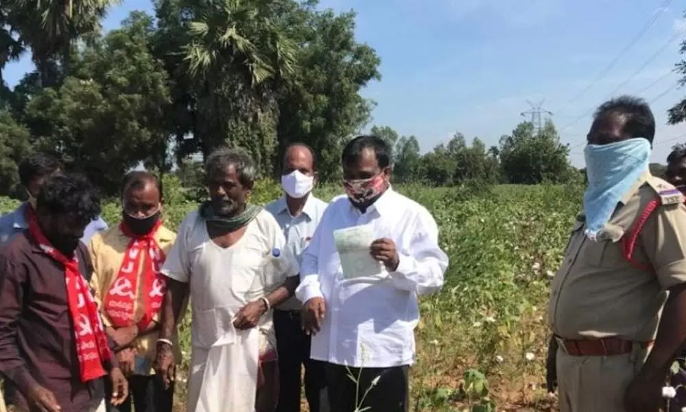 Tahsildar Yadagiri checking the pattadar passbook of farmer V Pedda Mallaiah during land investigation at survey number 70 at Raghavapuram crossroads on Friday