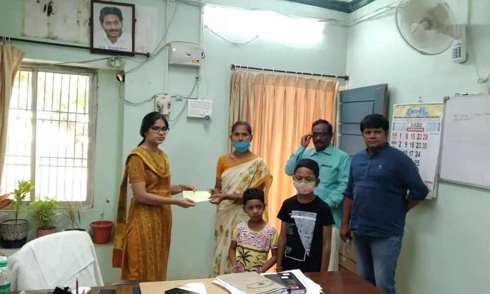 Nandyal Sub-Collector Kalpana Kumari hands over Rs 1 lakh cheque to Narayanamma, the wife of deceased surveyor, at her office in Kurnool on Monday