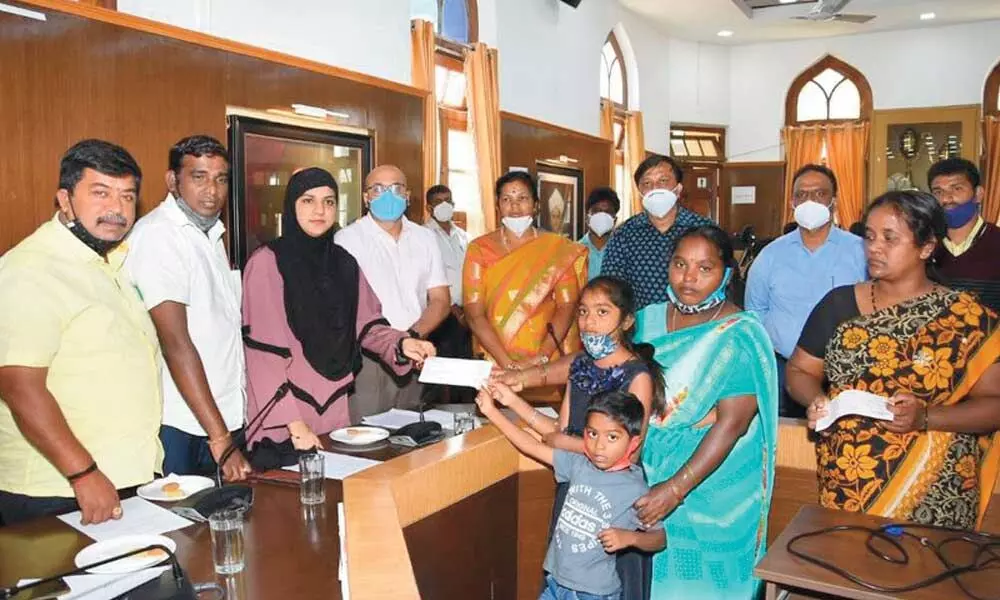 City Mayor Tasleem and Mysuru City Corporation Commissioner Gurudutt Hegde distributing Rs 30 lakh ex gratia each for the family of five employees of MCC who died of Covid-19 in Mysuru on Monday.