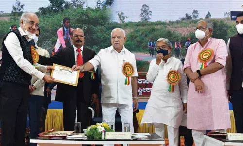 Chief Minister B.S. Yediyurappa hands over the school adoption certificate to Dharmasthala Education Trust Chairman Surendra Heggade