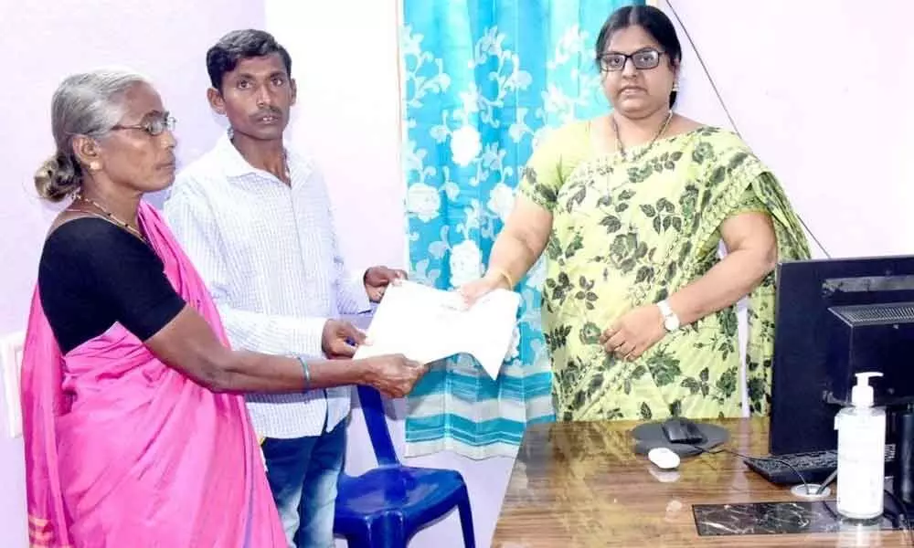 Kusumanchi Tahsildar and Joint Sub-Registrar handing over passbooks to a woman farmer in Khammam on Thursday