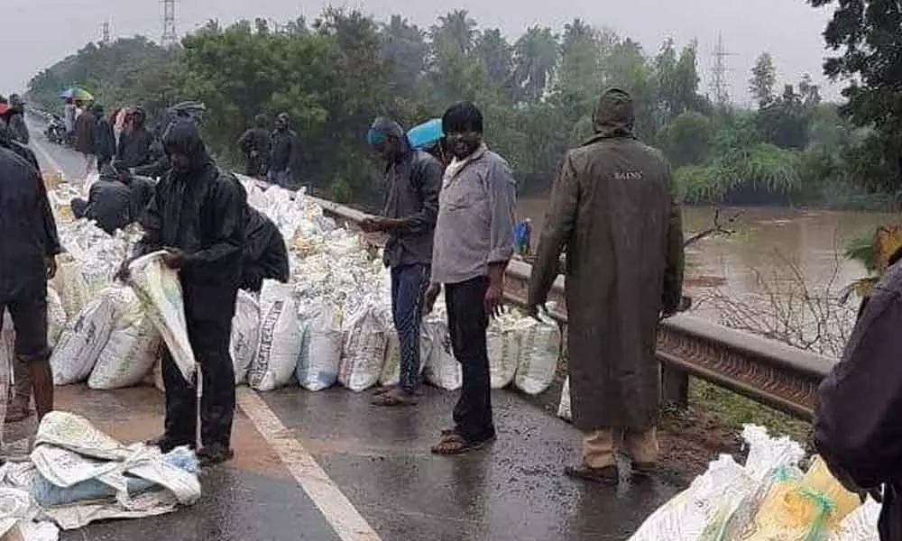 Officials arranging sandbags at the breached area on the NH-16 in Nellore on Sunday