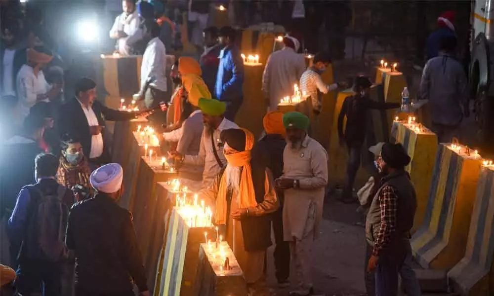 Farmers light candles on the occasion of birth anniversary of Guru Nanak Dev at the Singhu border in New Delhi on Monday