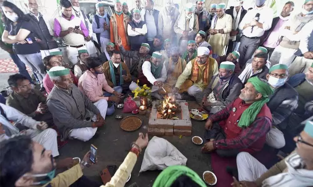 Farmers perform a havan during their ongoing agitation against new farm laws, at Ghazipur Delhi-UP border, in New Delhi on Wednesday